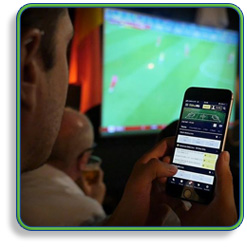 Man Checking His Sports Bet on His Phone With TV in The Back