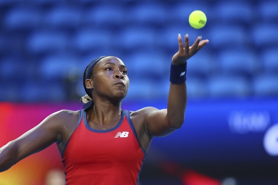 Coco Gauff prepares to serve in a tennis match.