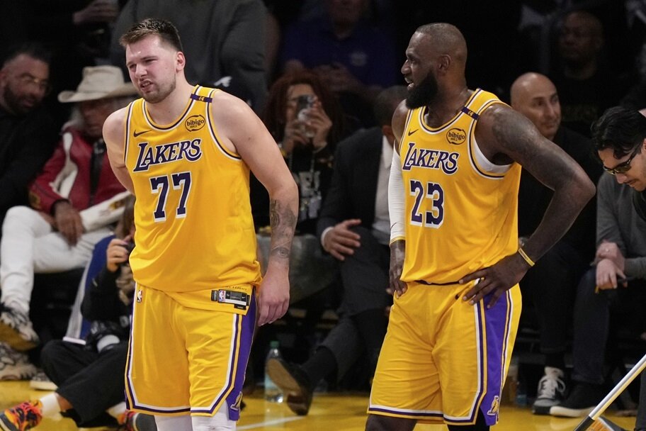 LeBron James watches Luka Doncic walk off the court after an injury.